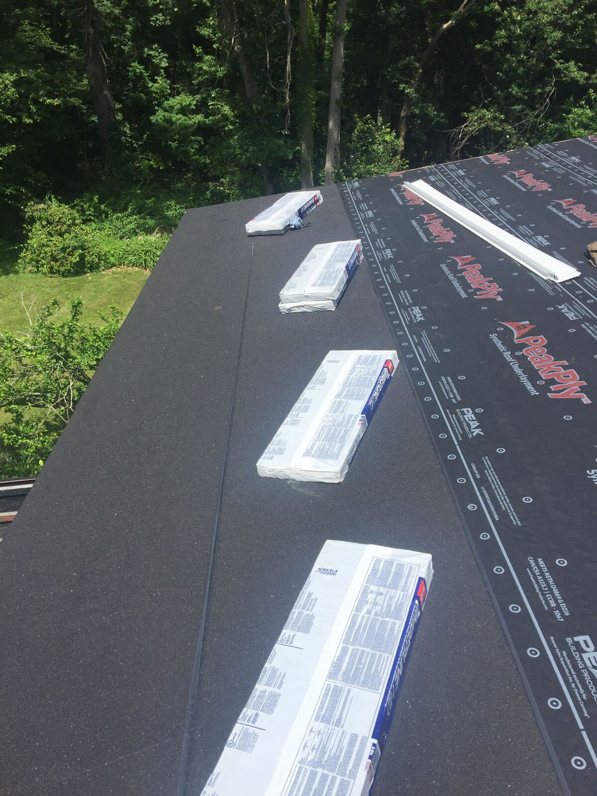 Roof replacement in progress — underlayment + shingle bundles staged